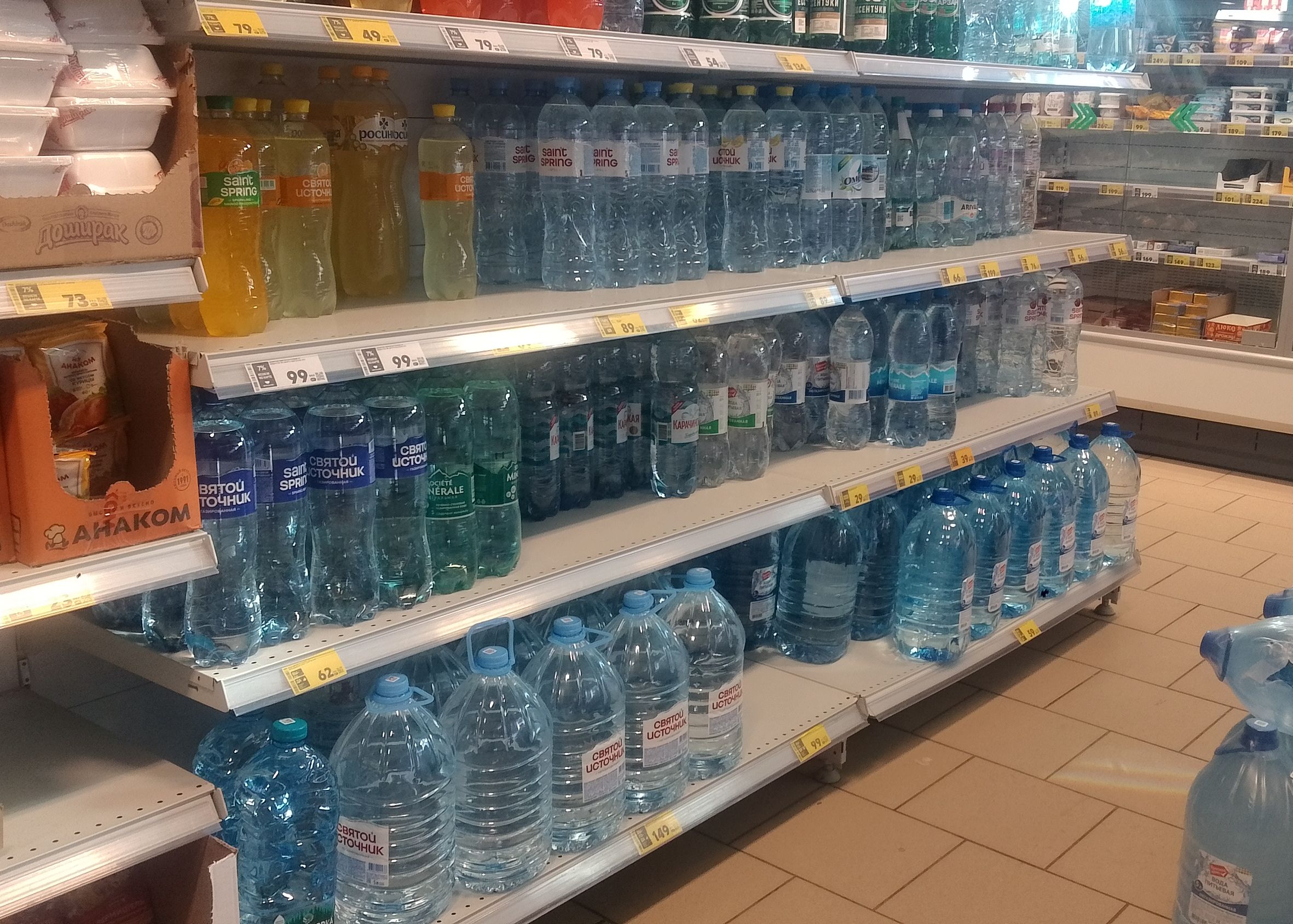 Rows of sealed drinking water bottles and large jugs stored on shelves