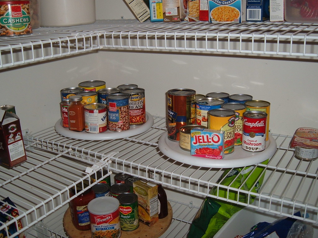 Canned goods organized on rotating racks on a pantry shelf