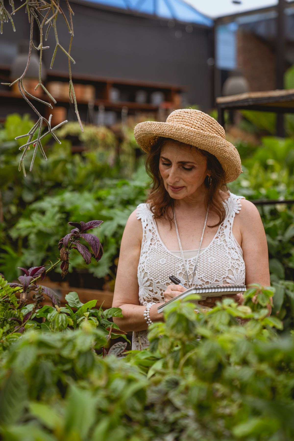 A gardener writing plans in a notebook among plants