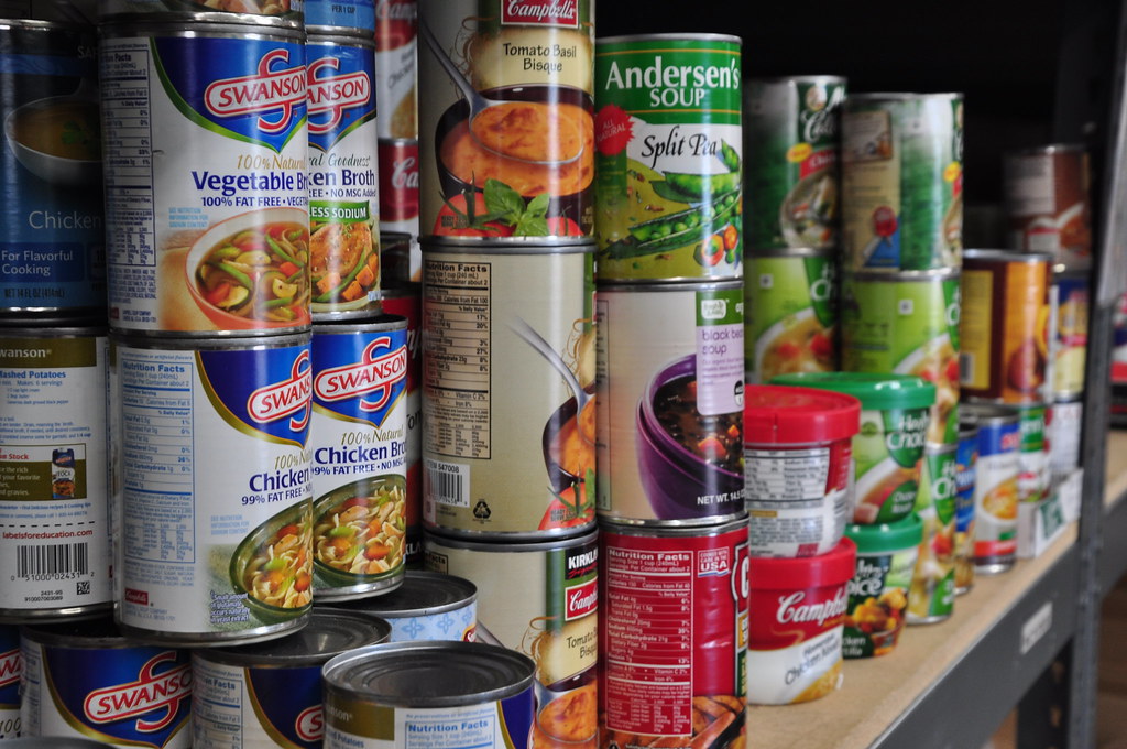 Shelves stacked deep with canned soups and other canned food in a home pantry
